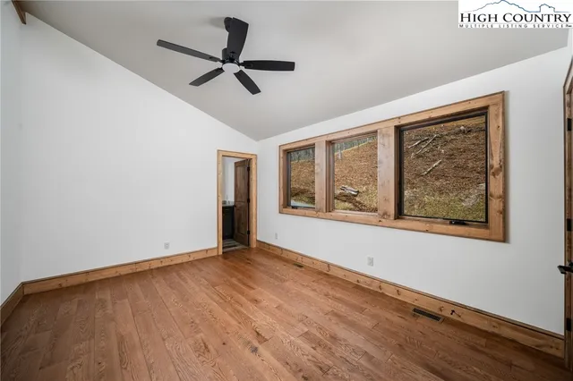 a view of an empty room with window and wooden floor