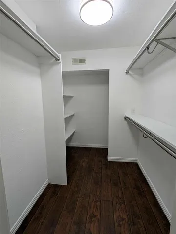 an empty room with wooden floor a ceiling fan and windows