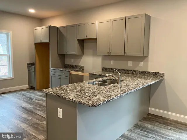 a kitchen with kitchen island granite countertop a sink stove and refrigerator
