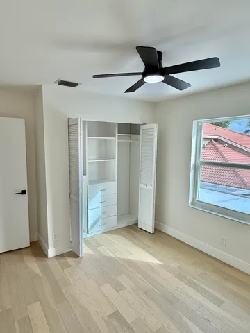 a view of an empty room with wooden floor and chandelier