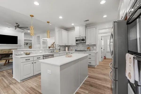 a kitchen with kitchen island granite countertop a sink cabinets and stainless steel appliances