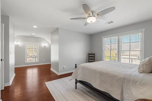 a spacious bedroom with a bed and wooden floor