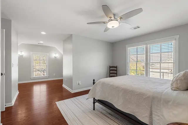 a spacious bedroom with a bed and wooden floor