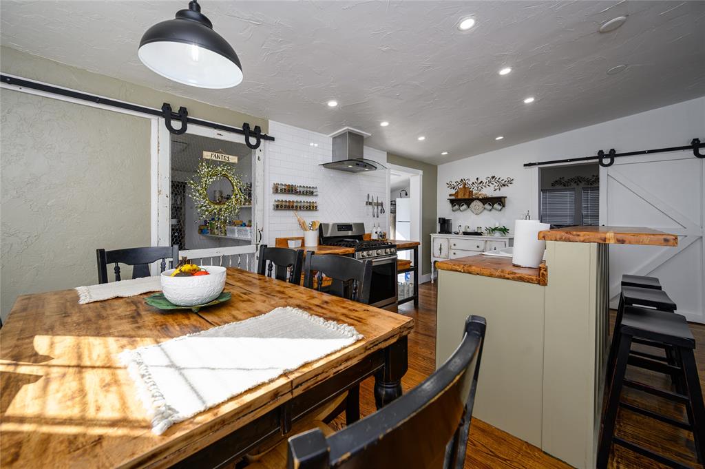4597 West Line Road Whitesboro, TX 76273 - Photo 16 of 31 a kitchen with stainless steel appliances kitchen island granite countertop a table chairs in it and wooden floors