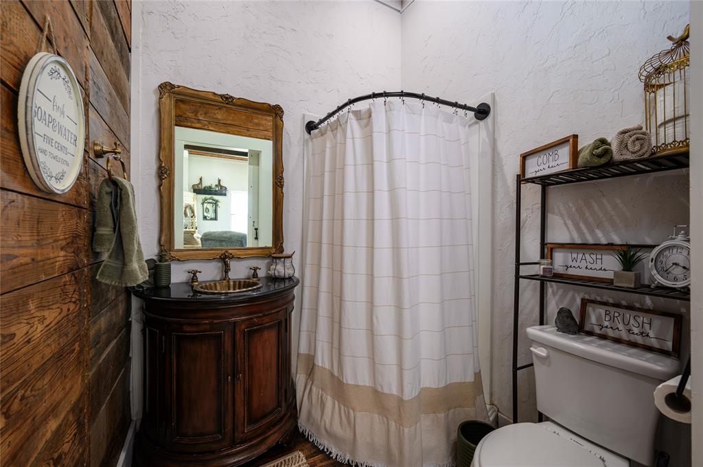 4597 West Line Road Whitesboro, TX 76273 - Photo 24 of 31 a bathroom with a sink a toilet and a mirror