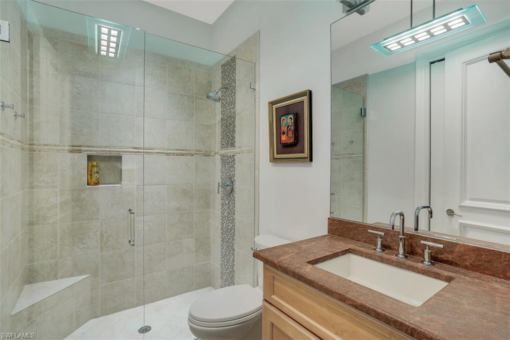 2343 Alexander Palm Naples, FL 34105 - Photo 22 of 35 a bathroom with a granite countertop sink a toilet a mirror and shower