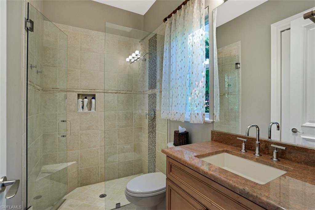 2343 Alexander Palm Naples, FL 34105 - Photo 26 of 35 a bathroom with a granite countertop sink a toilet a mirror and shower
