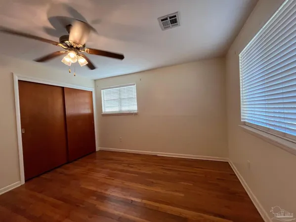 a view of an empty room with window and wooden floor