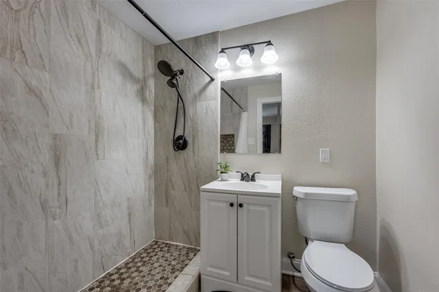 a bathroom with a toilet a sink a shower and vanity