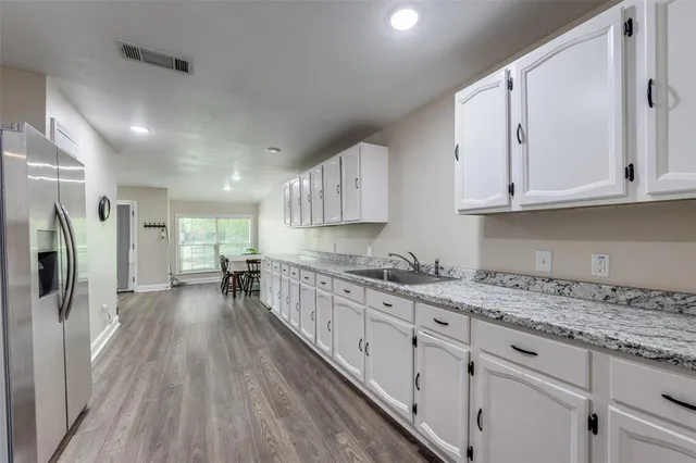 a kitchen with granite countertop a sink a refrigerator and wooden cabinets