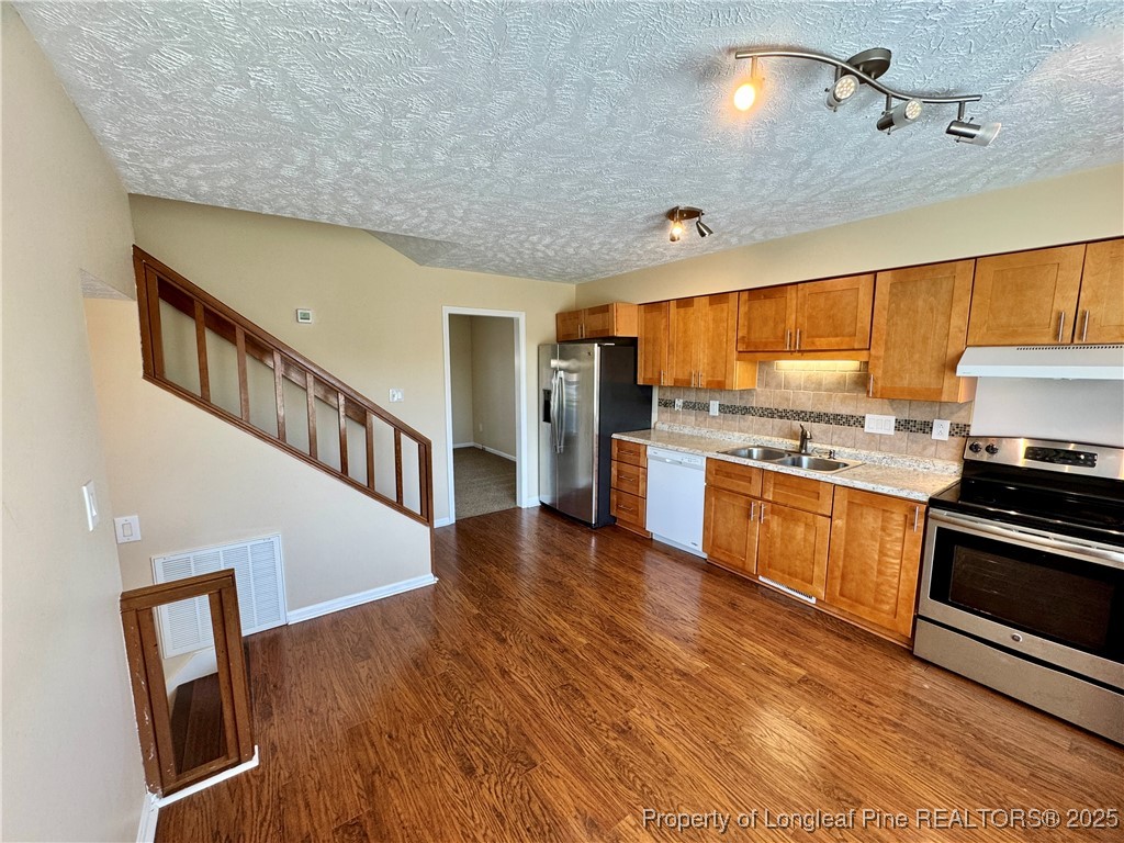 127 Nantahala Drive Linden, NC 28356 - Photo 8 of 22 a kitchen with stainless steel appliances a stove top oven a sink dishwasher and a refrigerator with wooden floor
