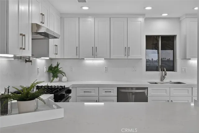a kitchen with stainless steel appliances kitchen island granite countertop a sink and a white cabinets