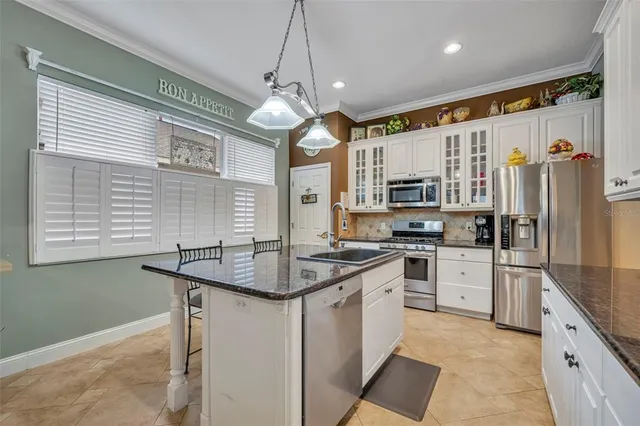 a kitchen with stainless steel appliances granite countertop a sink a stove a refrigerator and island