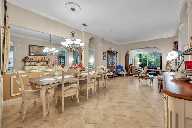 a view of a dining room and livingroom furniture a chandelier and kitchen view