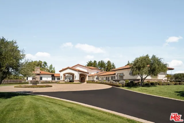 a white house with a large pool and lawn chairs