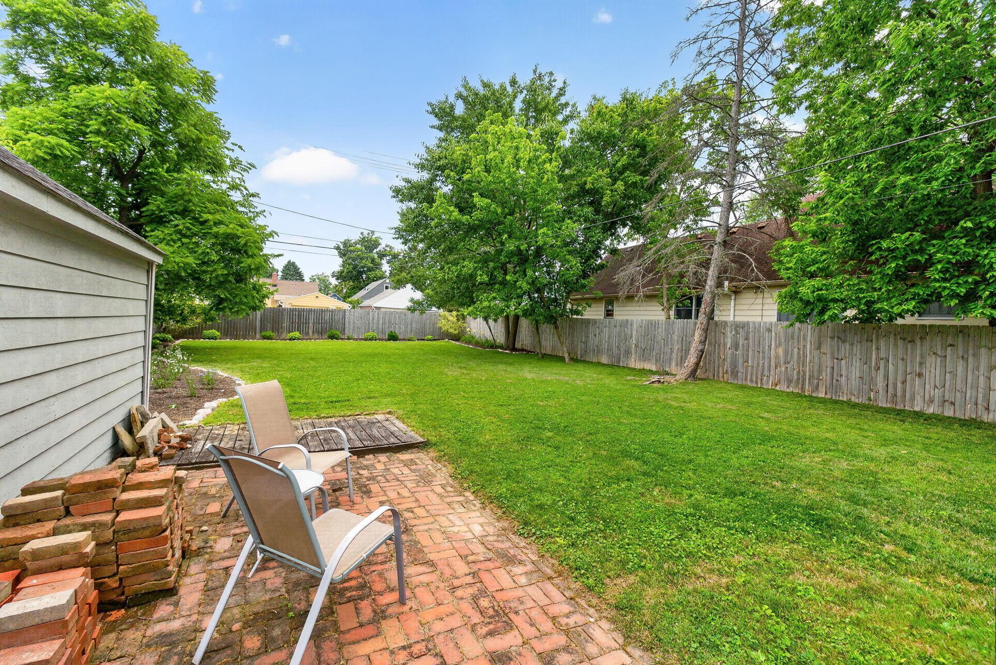 492 Wetmore Road Columbus, OH 43214 - Photo 43 of 55 Expansive backyard featuring a brick patio, manicured lawn, wood privacy fencing, and mature trees