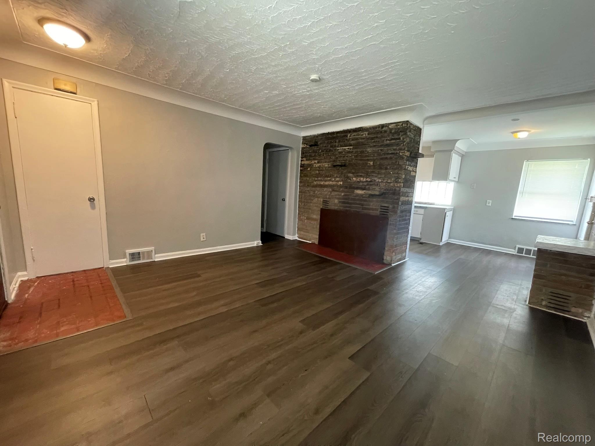 19800 Berg Road Detroit, MI 48219 - Photo 7 of 13 Spacious room featuring wood-finish flooring, a stone-clad fireplace, and neutral wall tones