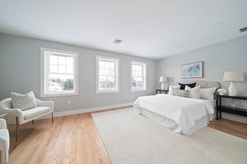 a spacious bedroom with a bed and wooden floor