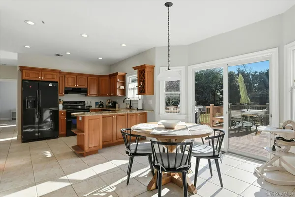 a kitchen with stainless steel appliances kitchen island granite countertop a refrigerator a sink a stove a dining table and chairs