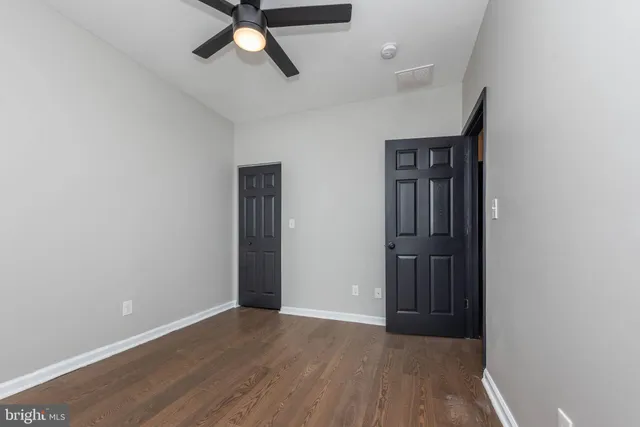an empty room with wooden floor a ceiling fan and windows