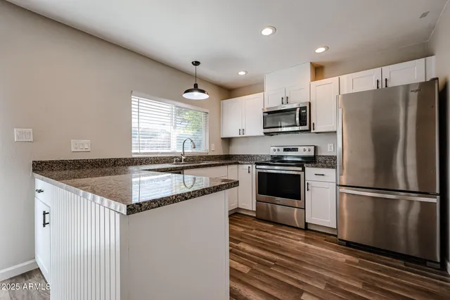 a kitchen with granite countertop a refrigerator and a stove top oven