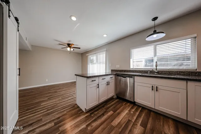 a kitchen with granite countertop a sink cabinets window and stainless steel appliances