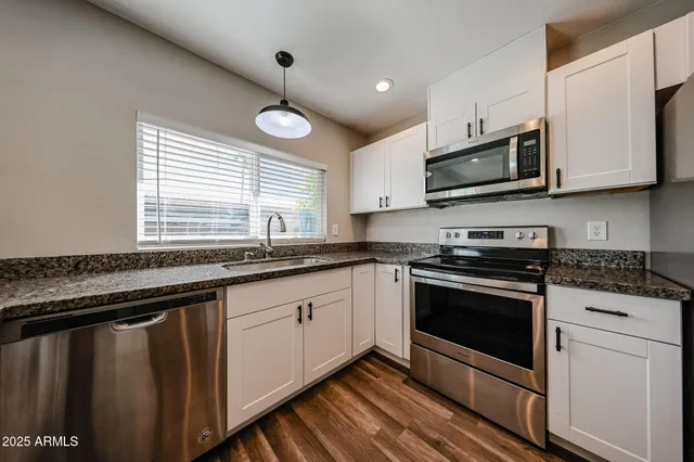a kitchen with stainless steel appliances granite countertop a sink a stove a microwave and wooden cabinets