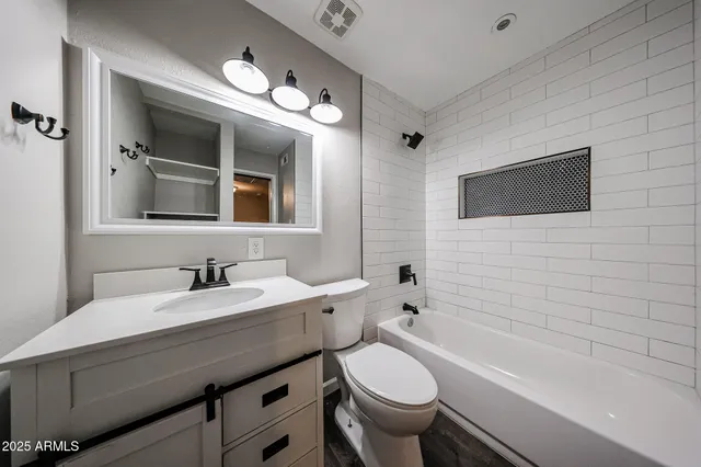 a bathroom with a granite countertop toilet sink a mirror a bathtub and shower