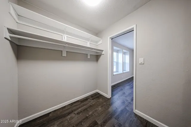 a view of an empty room with wooden floor and closet