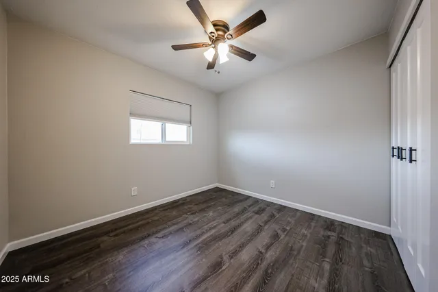 an empty room with windows and fan