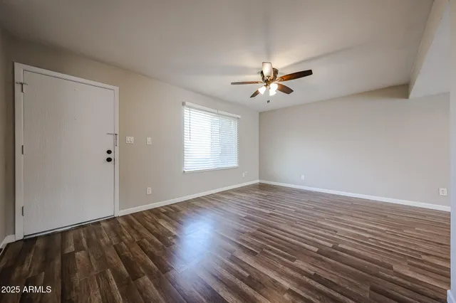 a view of empty room with wooden floor and fan
