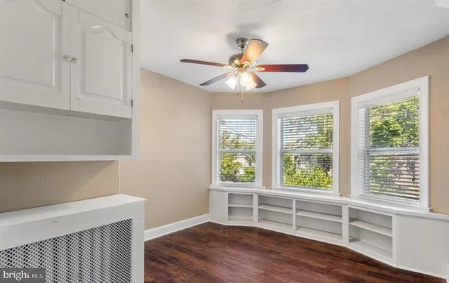 a view of an empty room with a window and wooden floor