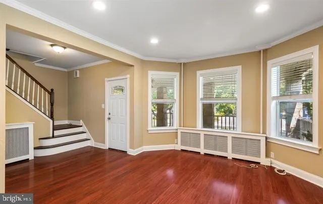 a view of an empty room with wooden floor and windows