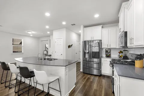 a kitchen with stainless steel appliances kitchen island granite countertop a sink and refrigerator