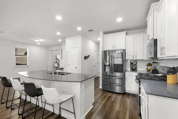 a kitchen with stainless steel appliances kitchen island granite countertop a sink and refrigerator