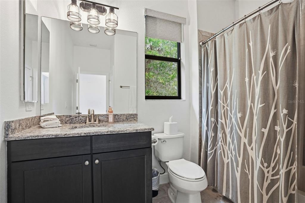 12417 Coralbean Court New Port Richey, FL 34654 - Photo 30 of 64 a bathroom with a granite countertop sink a toilet and a mirror