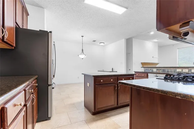 a large kitchen with stainless steel appliances granite countertop a refrigerator and a stove top oven