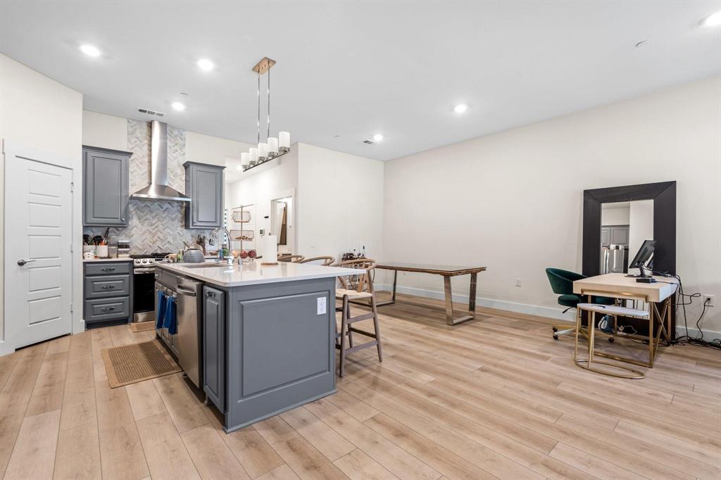 3781 Rochelle Court Prosper, TX 75078 - Photo 7 of 30 Kitchen with gray cabinets, an island with sink, light stone countertops, decorative backsplash, and light wood-style floors