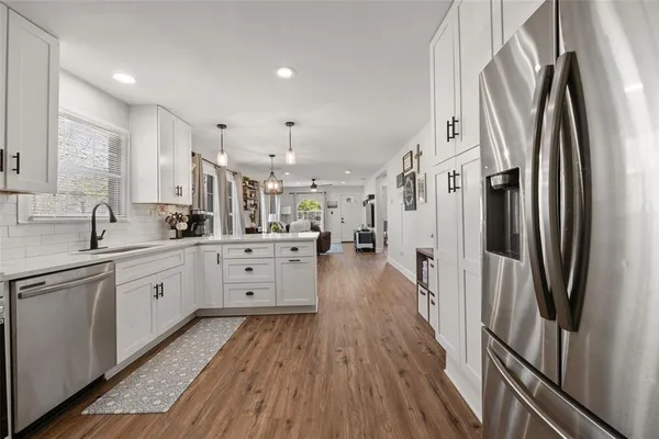 a large white kitchen with stainless steel appliances and a refrigerator