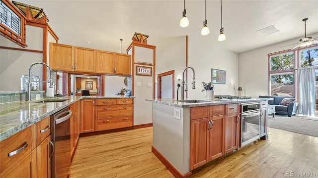 a kitchen with stainless steel appliances kitchen island granite countertop a stove a sink and a wooden floors