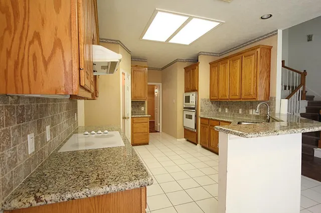 a large kitchen with granite countertop a sink and a refrigerator