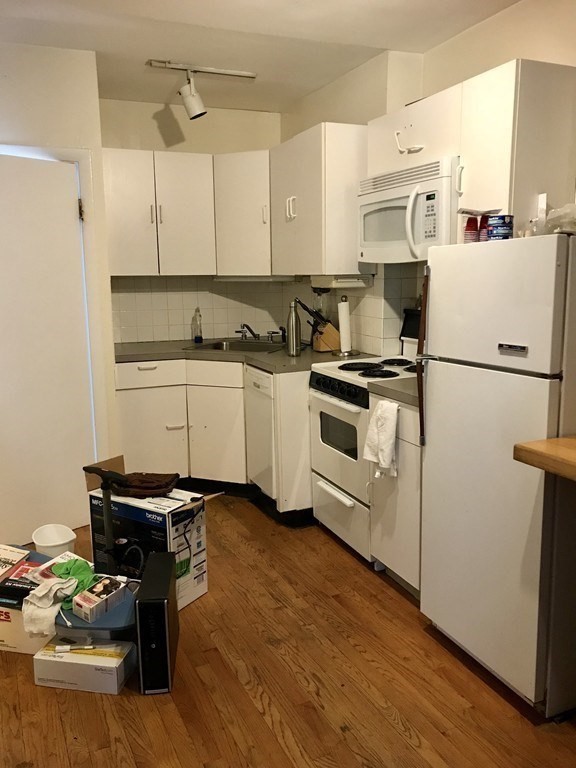 43-43A Grove Street, Unit 2 Boston, MA 02114 - Photo 3 of 6 a kitchen with a refrigerator a stove a sink dishwasher and white countertops with wooden floor