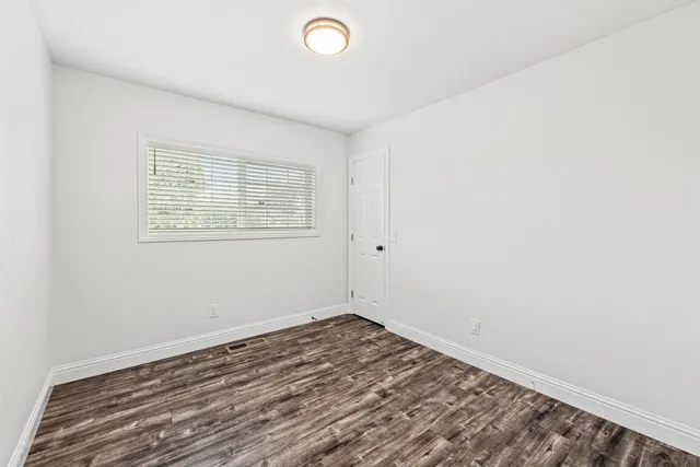 a view of an empty room with window and wooden floor