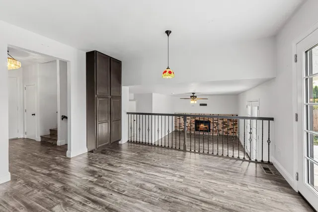 a open kitchen with stainless steel appliances granite countertop a refrigerator a stove top oven and a large window with wooden floor