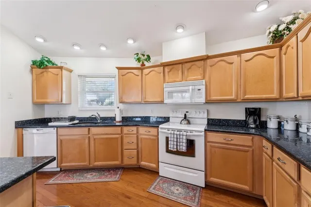 a kitchen with stainless steel appliances granite countertop wooden cabinets granite counter tops and a hard wood floors