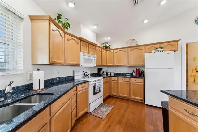a kitchen with granite countertop a sink a counter top space stainless steel appliances and cabinets