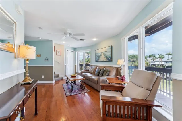 a living room with furniture a large window and wooden floor