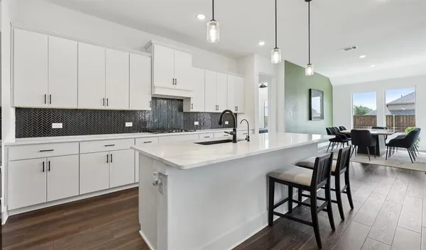 a kitchen with white cabinets and chairs