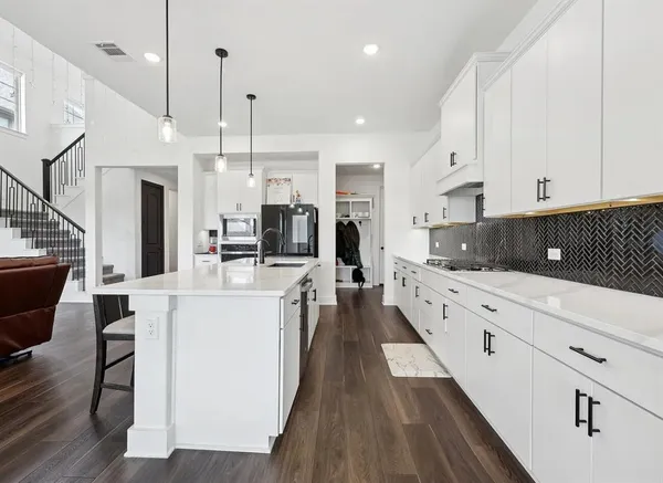 a large white kitchen with lots of counter space a sink appliances and cabinets