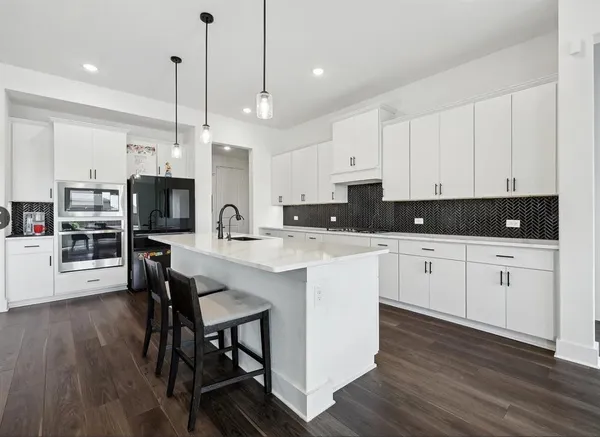 a kitchen with stainless steel appliances kitchen island granite countertop a stove a sink a microwave a center island and a cabinets